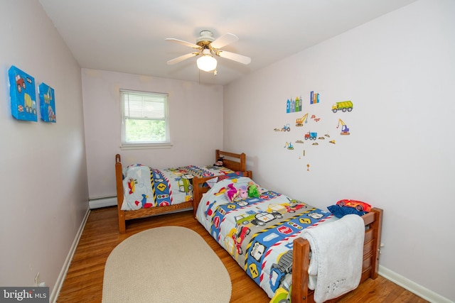 bedroom with ceiling fan, baseboards, wood finished floors, and a baseboard radiator