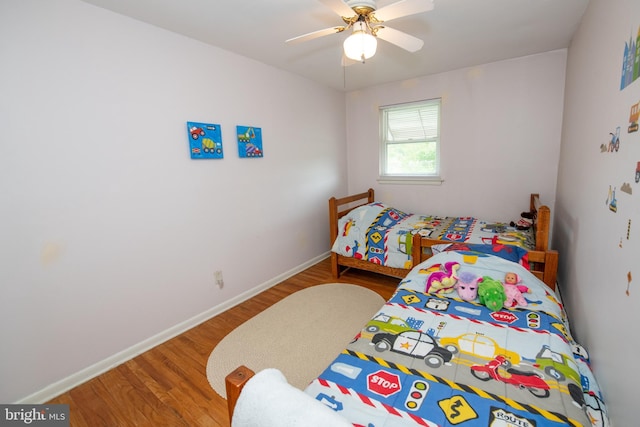 bedroom with ceiling fan, wood finished floors, and baseboards