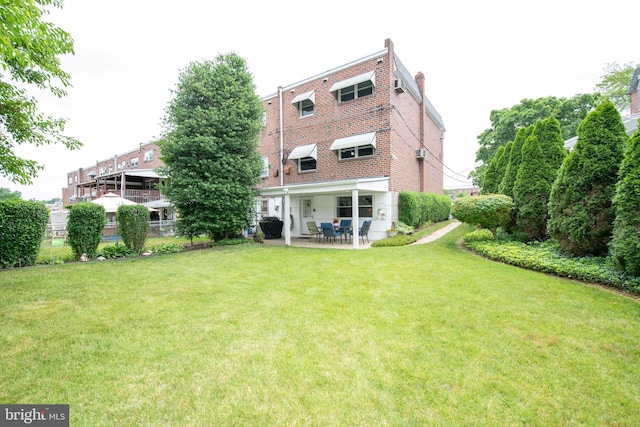 back of property with a lawn, fence, a patio, and brick siding