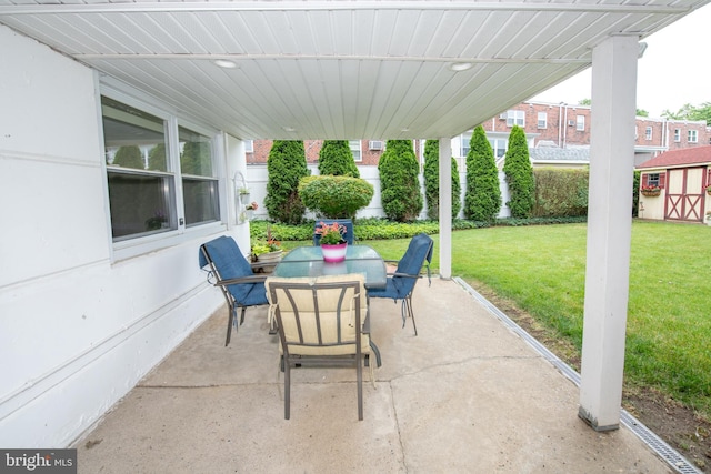 view of patio featuring outdoor dining space, a storage unit, and an outbuilding
