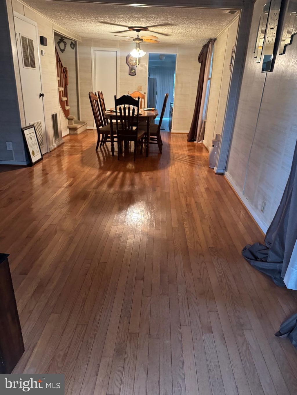 dining space featuring dark wood-style flooring, stairs, a textured ceiling, and a ceiling fan