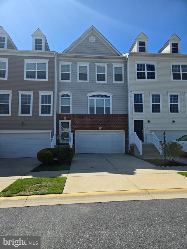 townhome / multi-family property with brick siding, a garage, and driveway