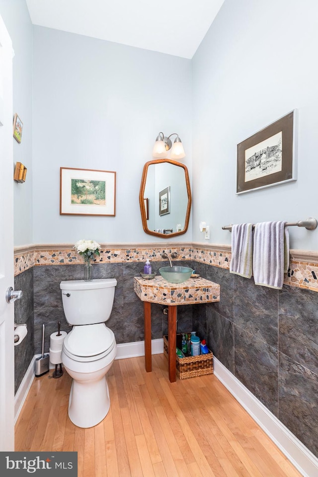 536 Yacht Club Dr, Ocean Pines, MD 21811 - half bathroom featuring tile walls, a wainscoted wall, toilet, wood finished floors, and a sink