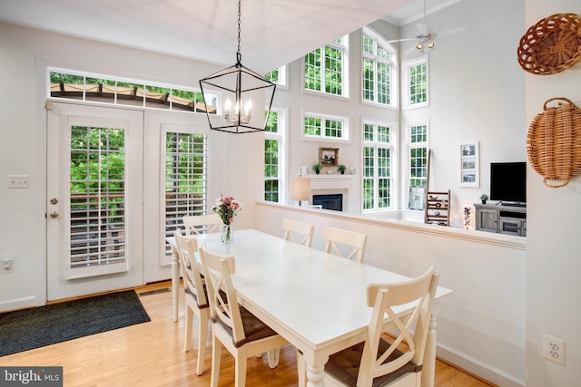 18565 Kerill Rd, Triangle, VA 22172 - dining area featuring light wood-style flooring, a glass covered fireplace, a chandelier, and a ceiling fan