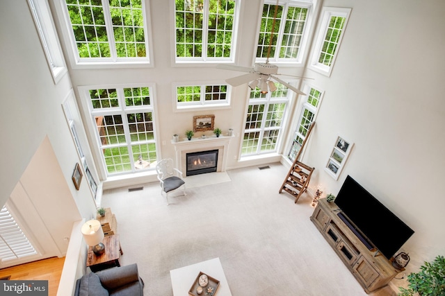 18565 Kerill Rd, Triangle, VA 22172 - living area with a towering ceiling, a fireplace with flush hearth, a ceiling fan, and healthy amount of natural light
