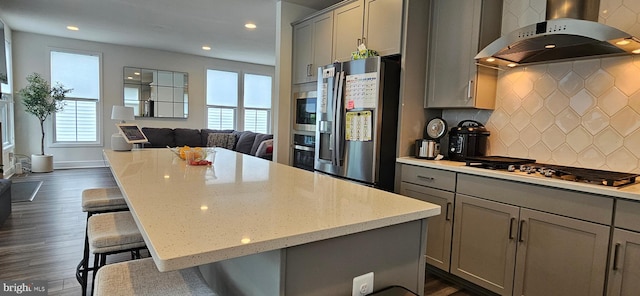 21340 Rainier Ln, Broadlands, VA 20148 - kitchen with gray cabinets, range hood, stainless steel appliances, open floor plan, and light stone counters