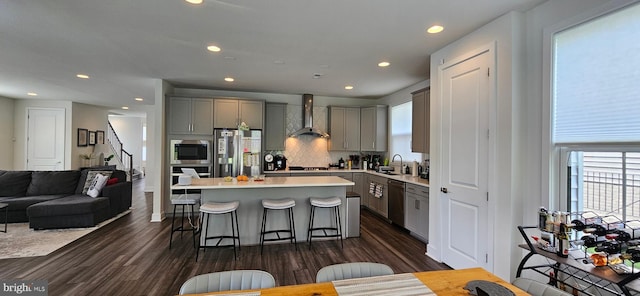 21340 Rainier Ln, Broadlands, VA 20148 - kitchen featuring wall chimney exhaust hood, gray cabinets, stainless steel appliances, a sink, and a breakfast bar