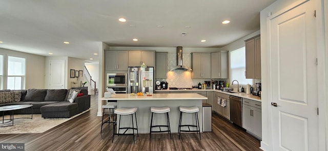 21340 Rainier Ln, Broadlands, VA 20148 - kitchen with wall chimney exhaust hood, gray cabinetry, stainless steel appliances, a breakfast bar, and recessed lighting