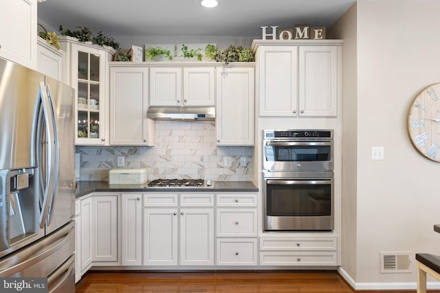 kitchen featuring dark countertops, visible vents, stainless steel appliances, and under cabinet range hood