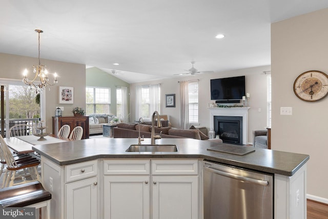 kitchen with open floor plan, a glass covered fireplace, stainless steel dishwasher, and a sink