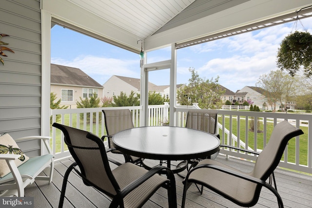deck with outdoor dining area, a residential view, and a lawn