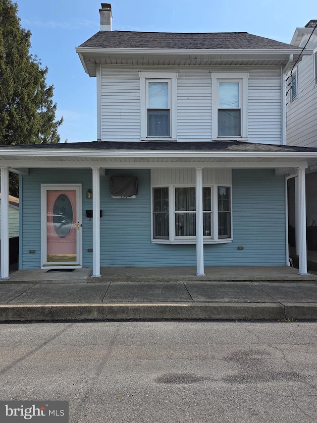 view of front of home featuring a porch and a chimney