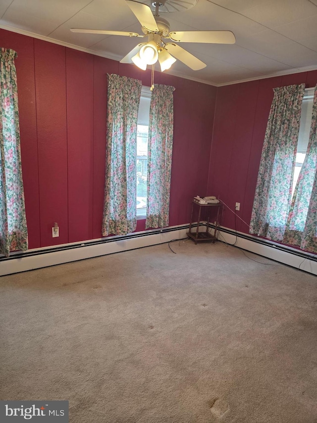 carpeted empty room featuring ceiling fan, ornamental molding, and a decorative wall