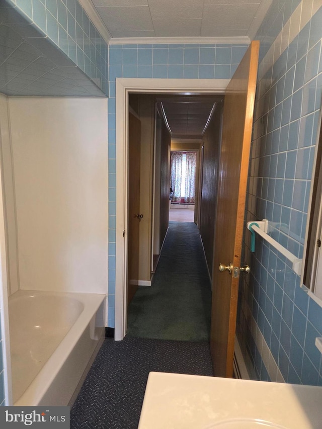 hallway with tile walls and dark colored carpet