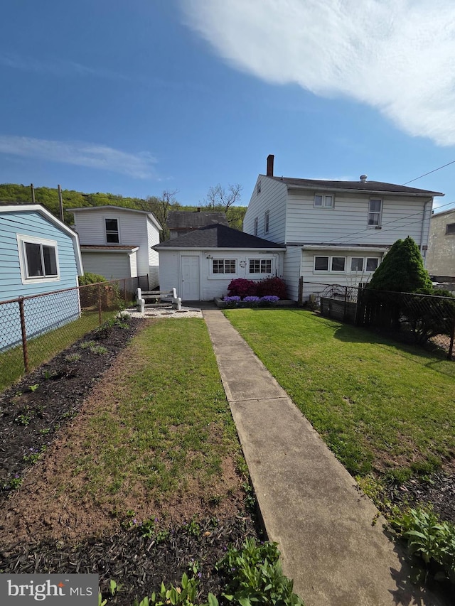 back of property featuring fence, a yard, and a chimney