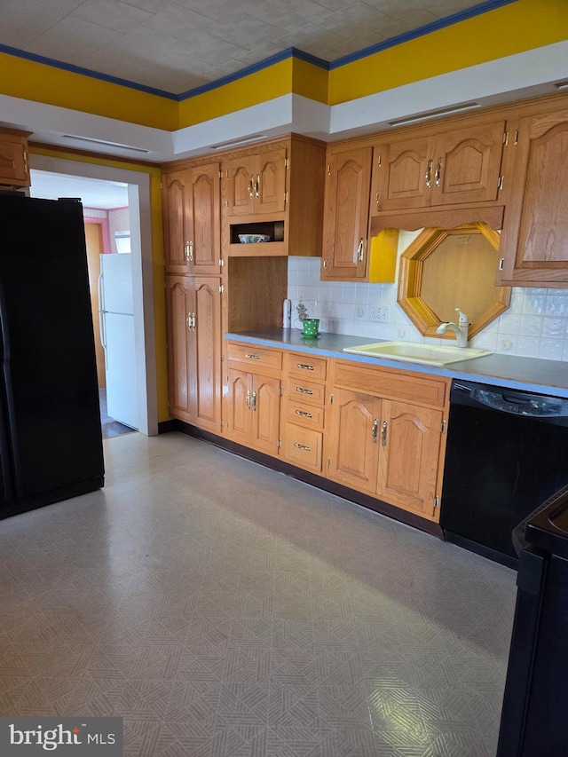 kitchen with a sink, light countertops, tasteful backsplash, and black appliances