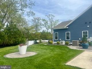 rear view of house with central air condition unit, a yard, and a patio area