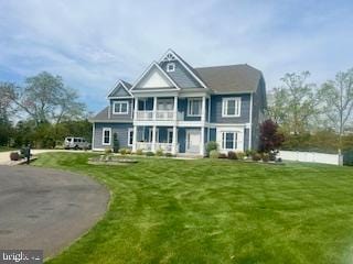 view of front of house featuring a front lawn and a balcony