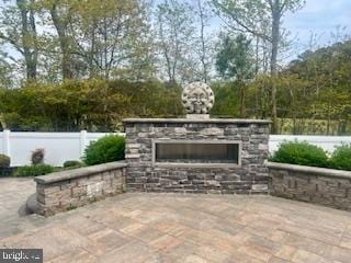 view of patio / terrace featuring an outdoor stone fireplace and fence