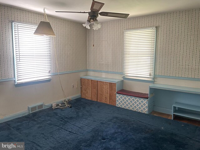 empty room with visible vents, a ceiling fan, and wallpapered walls
