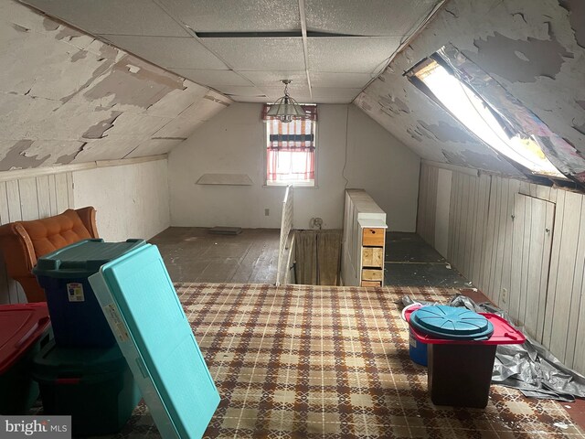 bonus room with wood walls and lofted ceiling