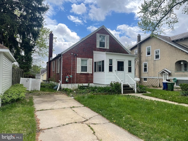 bungalow with brick siding, a front yard, entry steps, and fence