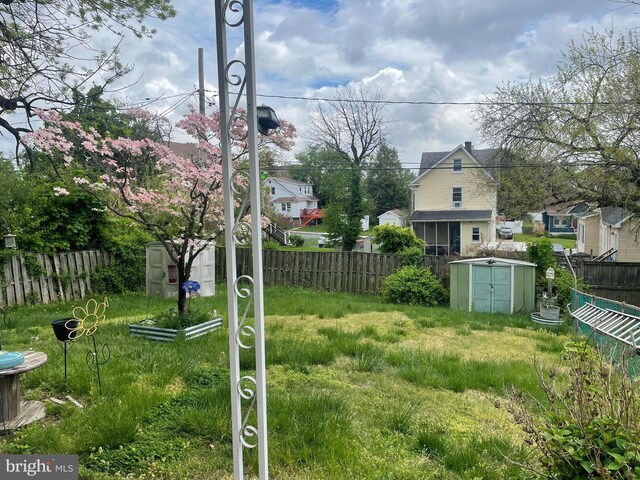 view of yard featuring a storage unit, an outdoor structure, and a fenced backyard