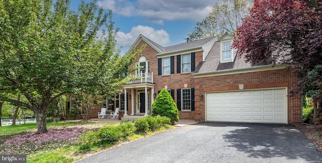 view of front of property featuring brick siding, a garage, driveway, roof with shingles, and a balcony