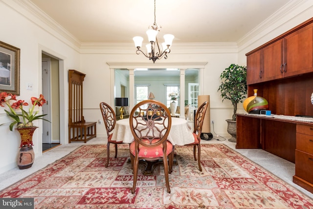 dining area featuring decorative columns, a notable chandelier, light carpet, and crown molding