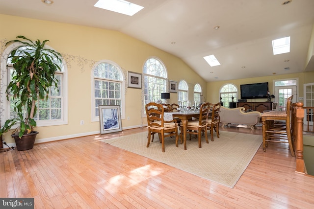 dining area featuring lofted ceiling with skylight, baseboards, and wood-type flooring