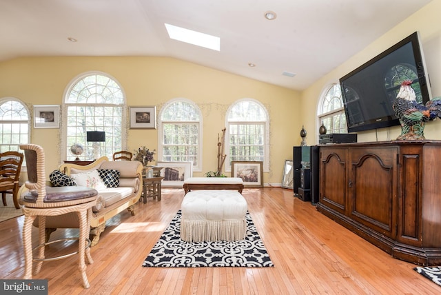 living area with light wood-type flooring and lofted ceiling with skylight