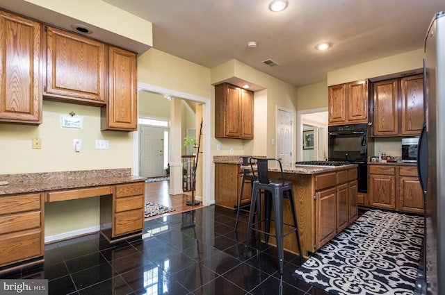 kitchen featuring a breakfast bar, a kitchen island, brown cabinets, built in study area, and baseboards