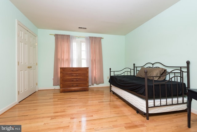 bedroom with wood finished floors, visible vents, and baseboards