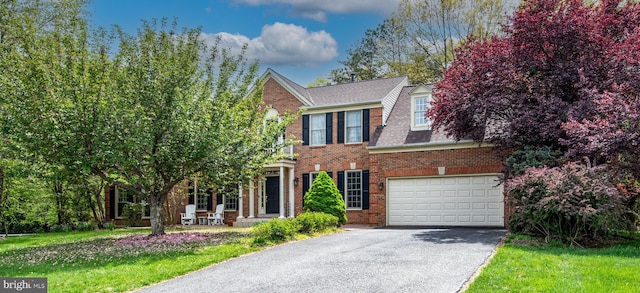 view of front of home featuring a front lawn, a garage, a shingled roof, aphalt driveway, and brick siding