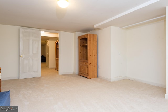 finished below grade area featuring baseboards and light colored carpet