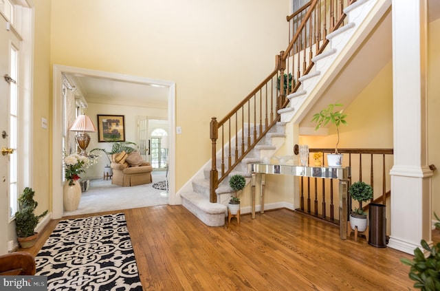 entrance foyer with stairway, wood finished floors, and a high ceiling