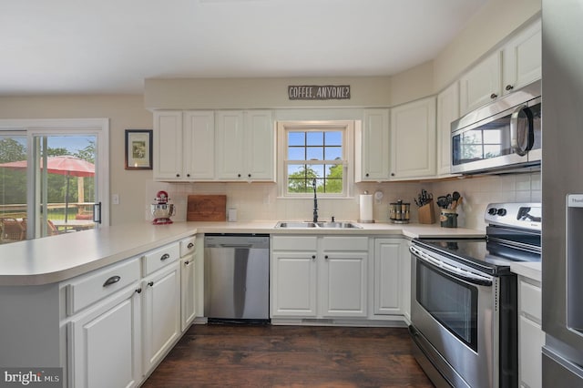 kitchen featuring a peninsula, a sink, stainless steel appliances, light countertops, and tasteful backsplash