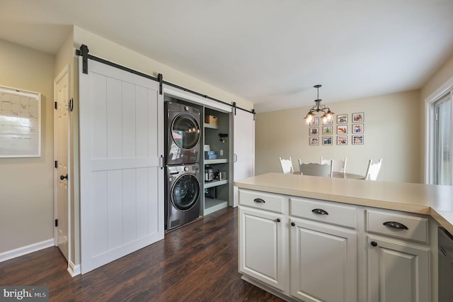 laundry area featuring stacked washer and dryer, laundry area, dark wood-style flooring, and a barn door