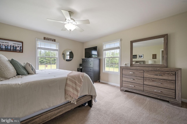 bedroom featuring light colored carpet, baseboards, and a ceiling fan