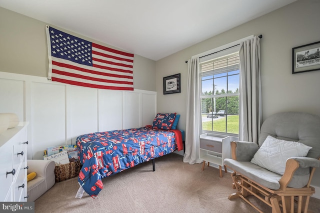 bedroom with a wainscoted wall, a decorative wall, and carpet floors