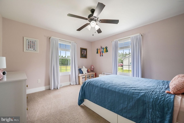 carpeted bedroom with multiple windows, baseboards, and a ceiling fan