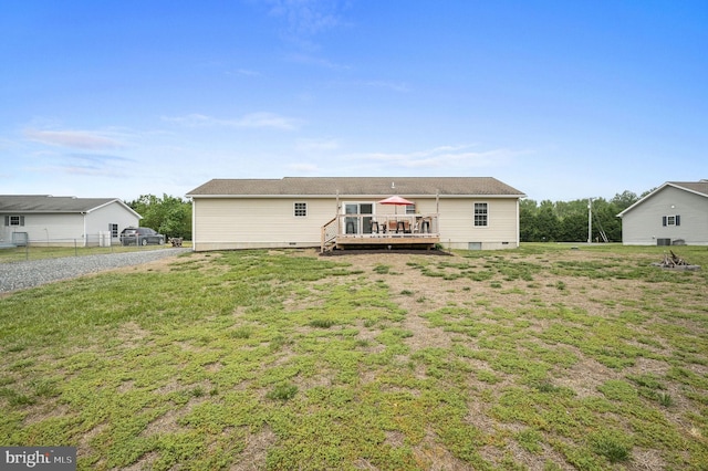 rear view of house with a lawn, fence, and a wooden deck