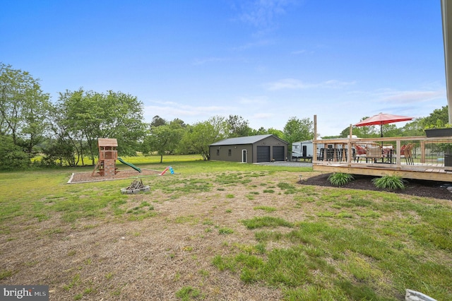 view of yard with an outbuilding, a wooden deck, a garage, and a playground