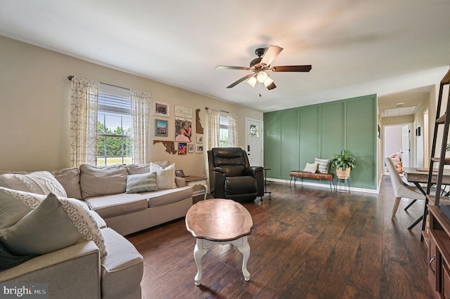 living room with attic access, dark wood-style flooring, and ceiling fan