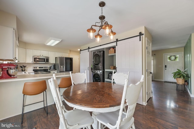 dining room featuring stacked washing maching and dryer, dark wood finished floors, and a barn door