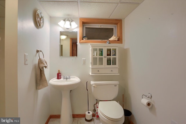 bathroom with a paneled ceiling, a sink, tile patterned floors, toilet, and baseboards