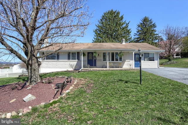 ranch-style house featuring a porch, a front lawn, driveway, and fence