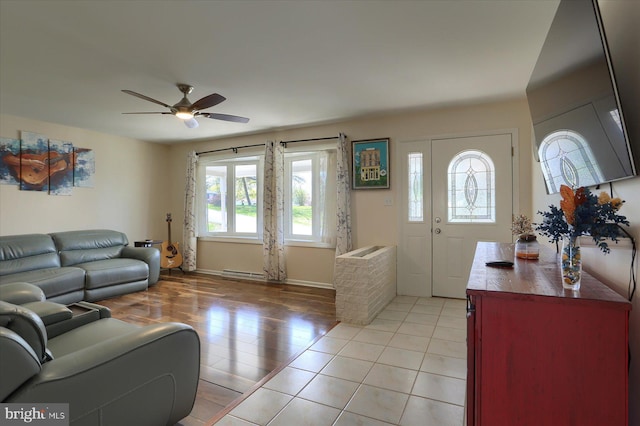 living area with baseboards, light tile patterned floors, a ceiling fan, and a baseboard radiator