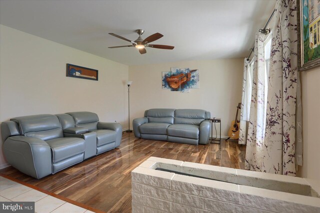 living room featuring baseboards, wood finished floors, and a ceiling fan