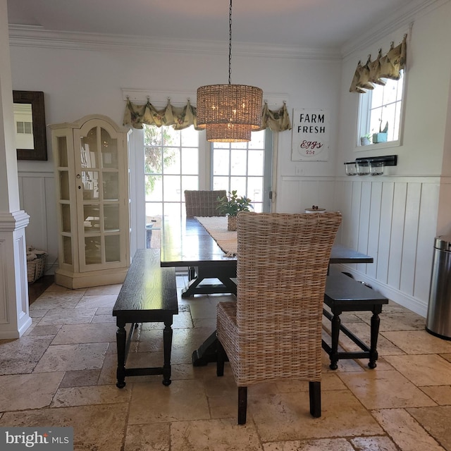 dining room featuring stone tile floors, ornamental molding, an inviting chandelier, and plenty of natural light